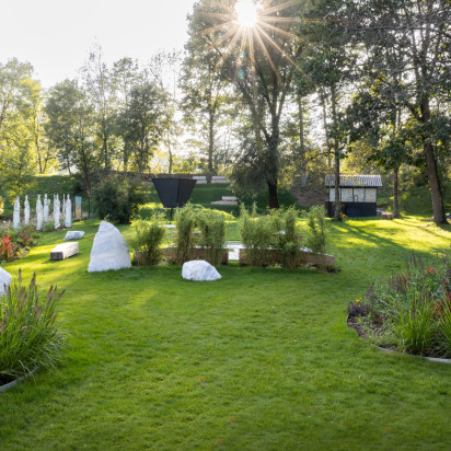 Skulpturenpark mit Sonnenschein, Bäumen und einer modernen Hütte