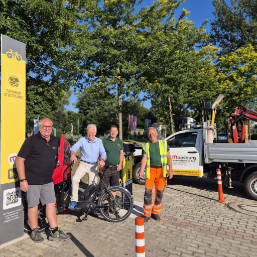 Fahrradstützpunkt Moosburg: Vier Männer stehen vor einem gelben Schild und einem Lastwagen.