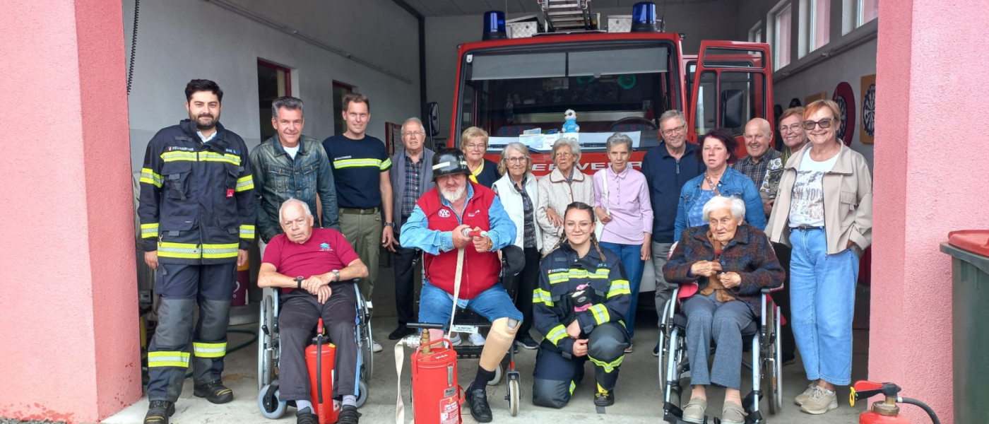 Feuerwehrleute und Bürger vor einem Feuerwehrauto in Österreich