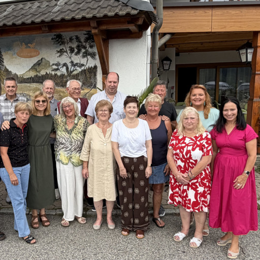 Gruppe von Menschen vor einem Gasthof mit Wandmalerei in Tirol