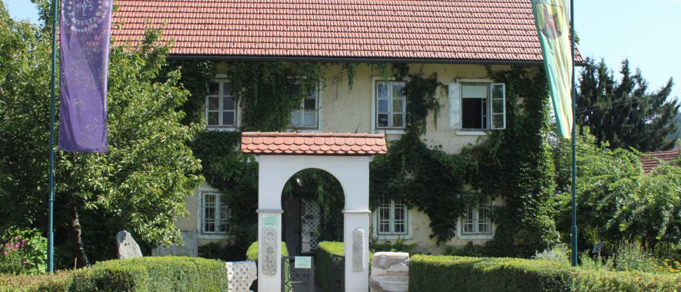 Haus in Moosburg mit Efeu-Bewuchs und Fahnen vor dem Eingang