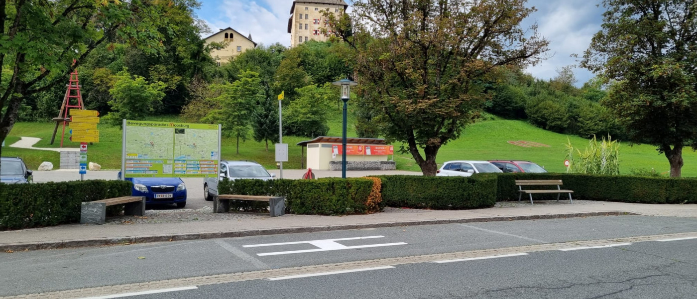Bewegungsparadies Moosburg mit Karte und Sitzbänken vor bewaldeten Hügeln