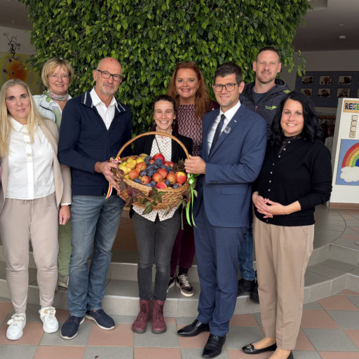 Gruppe mit Obstkorb vor grüner Hecke