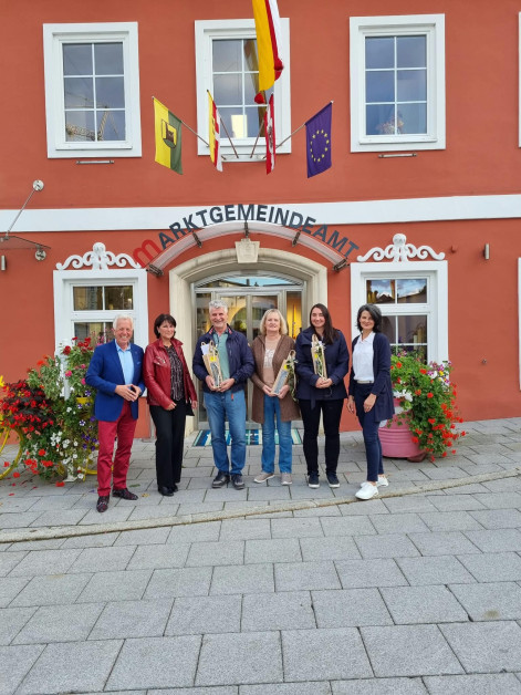 Marktgemeindeamt: Sechs Personen stehen vor dem Gebäude mit Blumen.